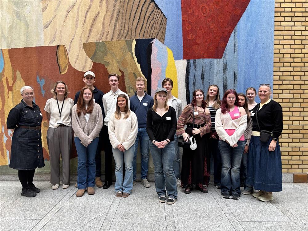 Et gruppebilde med alle som var med på turen. De står inne på stortinget foran veggen hvor politikere ofte blir intervjuet. - Klikk for stort bilde