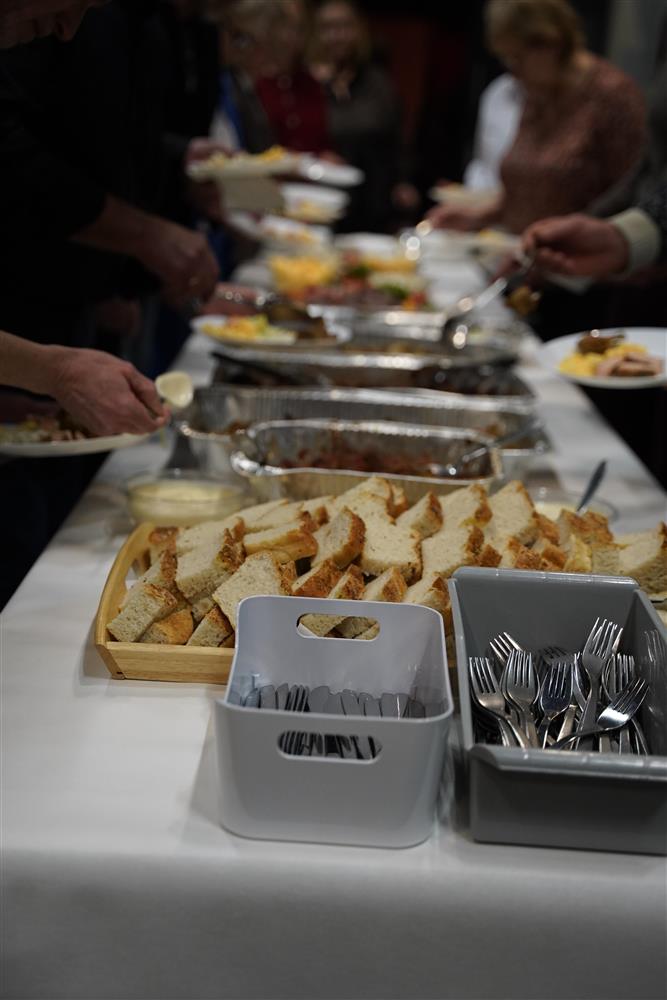 Et langt bord med diverse mat, flere folk som forsyner seg. - Klikk for stort bilde