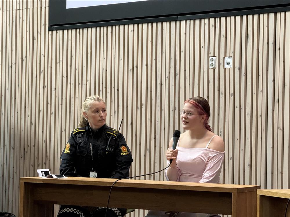 Panelsamtale, en ung jente og en politikonstabel som sitter sammen bak et bord  - Klikk for stort bilde