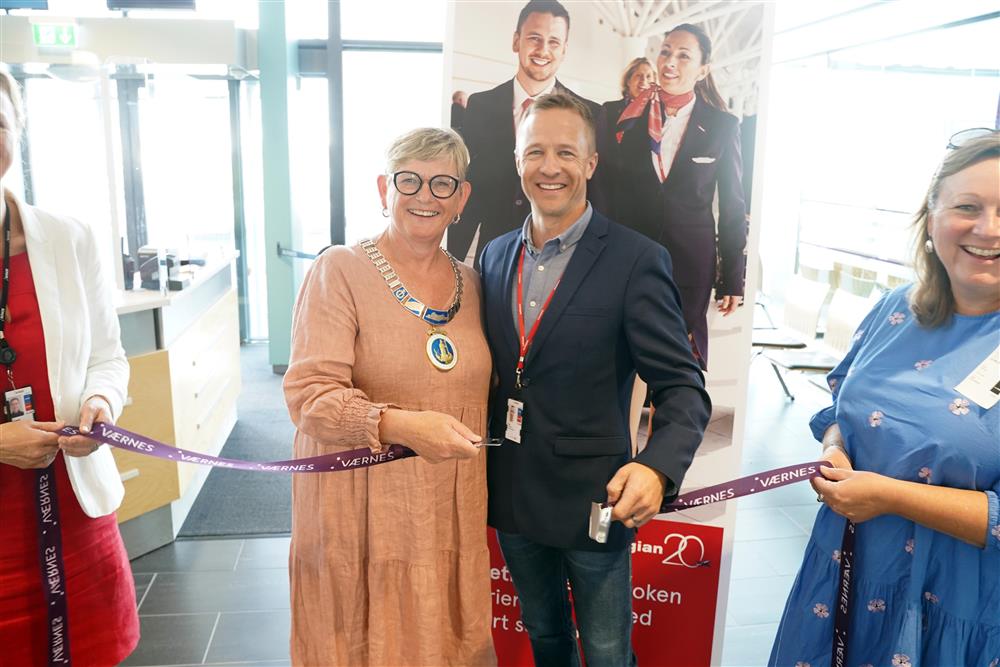 Ordføreren og representant fra Norwegian som smiler og ser rett i kamera. De har nettopp &quot;klippet snoren&quot; som i dette tilfellet er et sikkerhetsbelte som de har åpnet. - Klikk for stort bilde