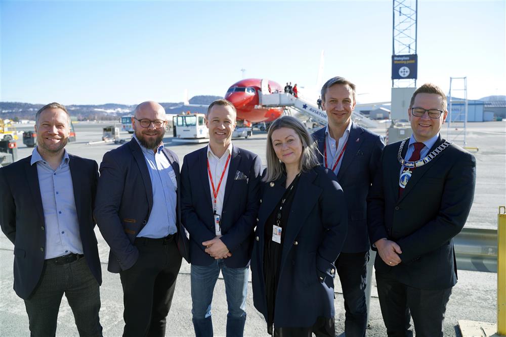 8 personer utendørs foran et norwegian fly - Klikk for stort bilde