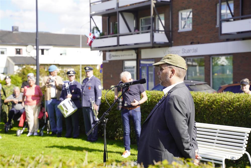 Veteran representant Geirr Tjash Hagen holder sin tale, i bakgrunnen står publikum og deler av Luftforsvarets musikkorps. - Klikk for stort bilde