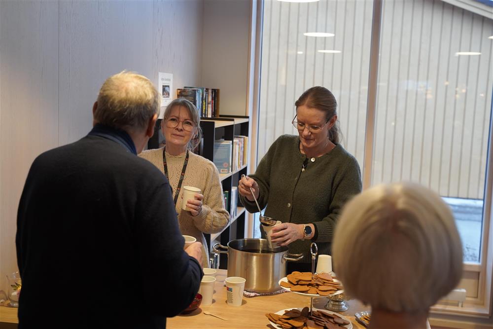 To ansatte som gir ut pepperkaker og gløgg til ansatte, beboere og besøkende innendørs på Fosslia omsorgsenter. - Klikk for stort bilde