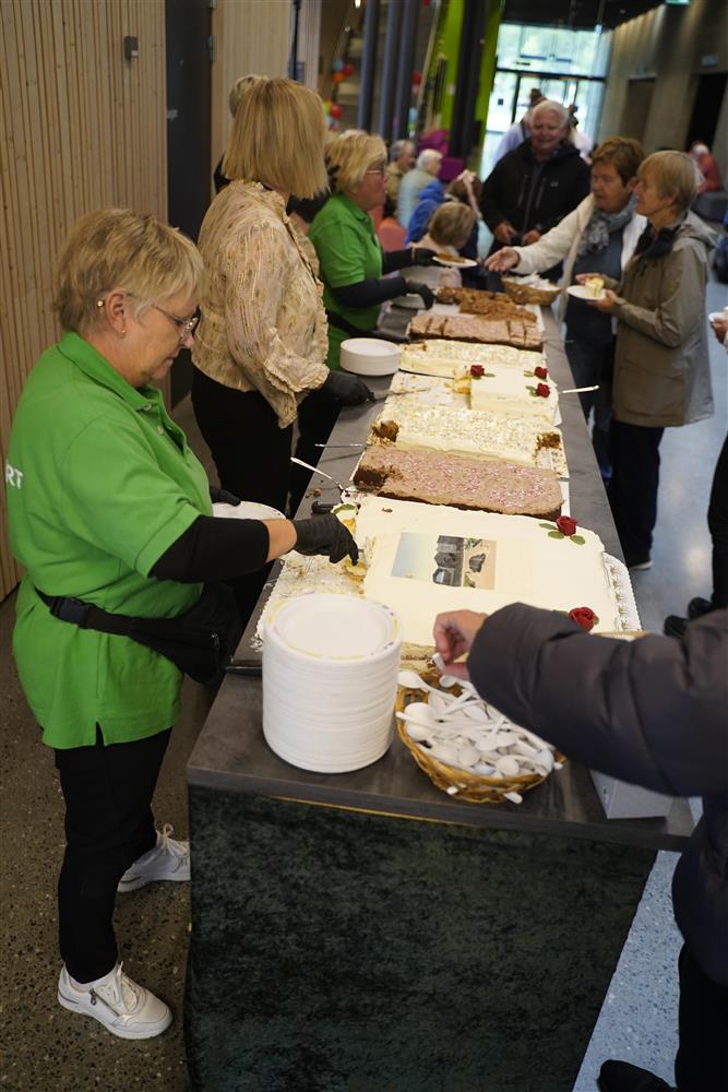 Mange folk i kø for å få kake. Frivillige kulturverter bidrar med å dele opp og dele ut kake. - Klikk for stort bilde