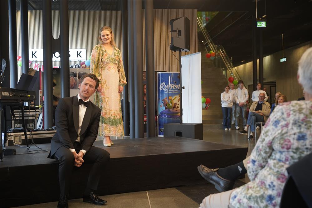 To operasangere på scenen i foajeen, mannen sitter og kvinnen står. - Klikk for stort bilde