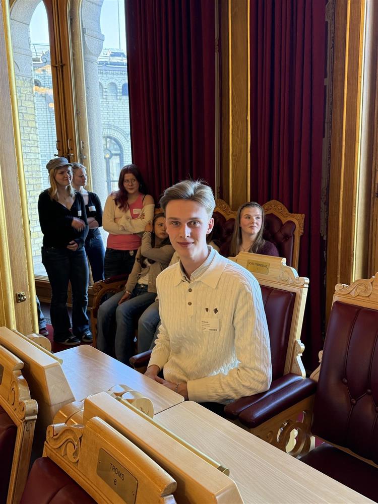 Iver som sitter i en av stolene inne i stortingssalen, flere andre fra rådet er rundt - Klikk for stort bilde