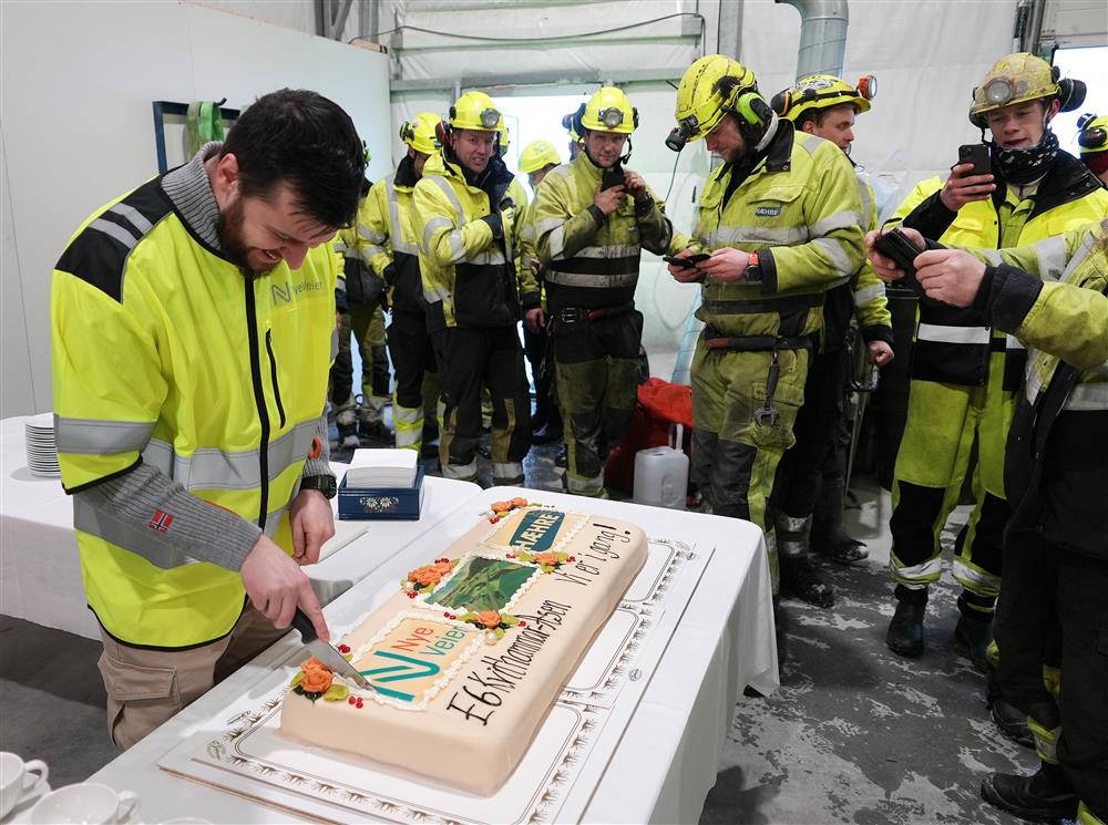 Flere anleggsarbeidere som står rundt en stor kake med skriften &quot;E6 Kvithammar – Åsen Vi er i gang!&quot; med diverse logoer  - Klikk for stort bilde