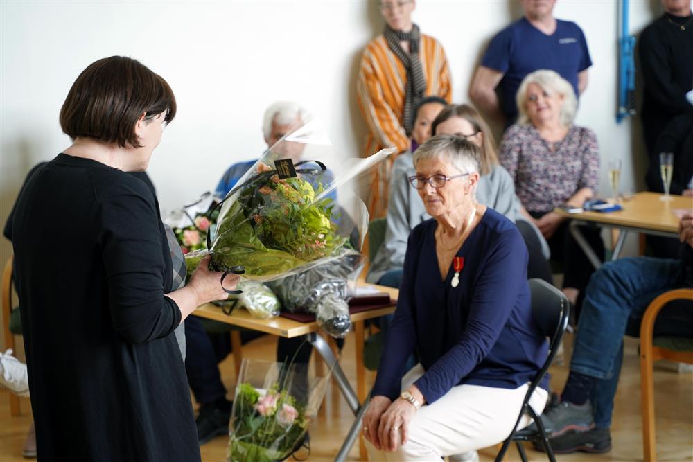 Dame som holder tale og gir blomsterbukket til en annen dame - Klikk for stort bilde