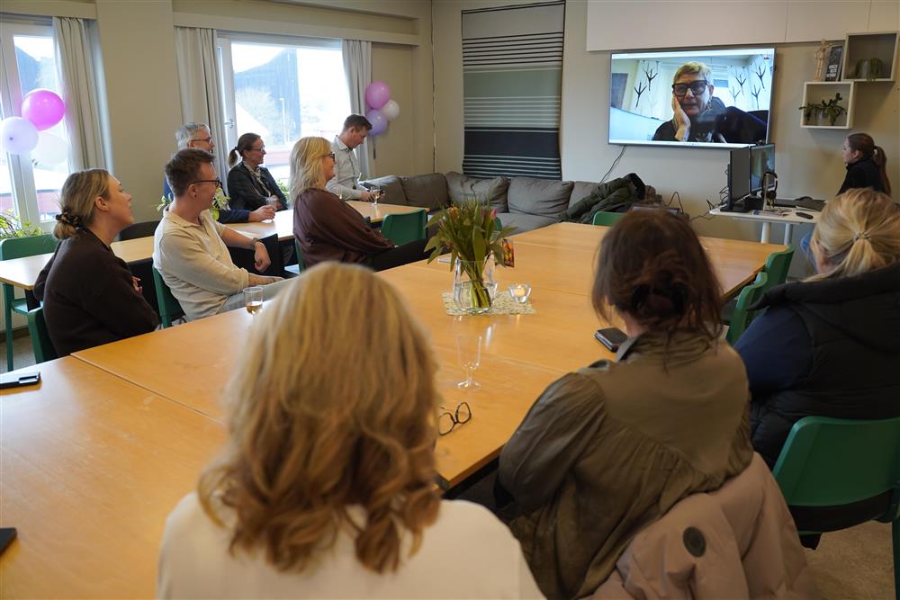 ti personer rundt et bord, på storskjerm er ordføreren. - Klikk for stort bilde
