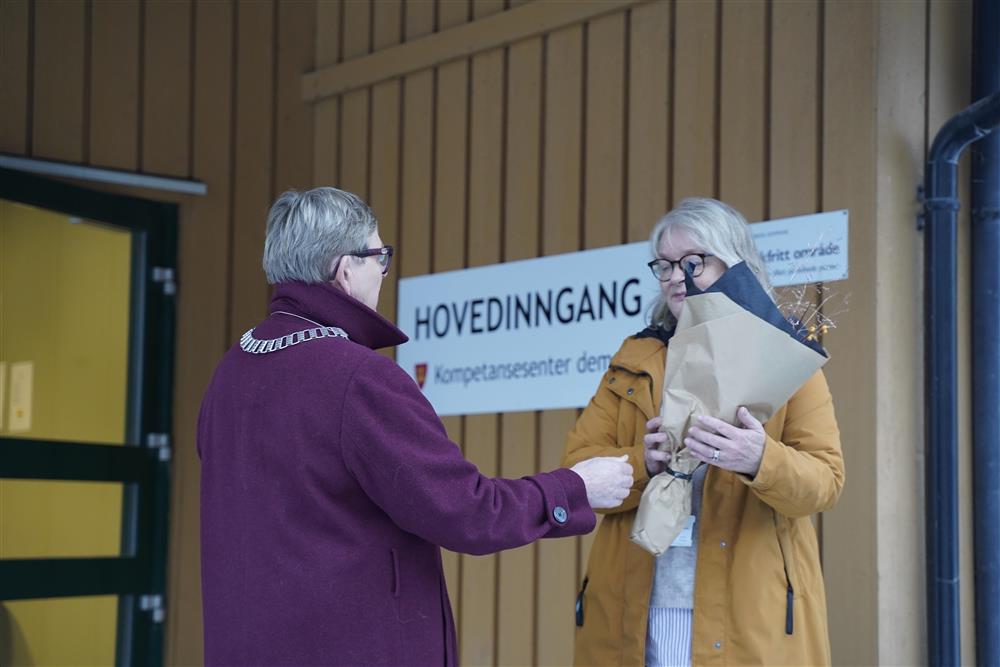 Ordføreren gir en stor blomsterbukket til Skjervold, de står ute foran hovedinngangen. - Klikk for stort bilde